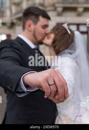 Kiss of the bride and groom, Joyfully show the rings. Focus on rings, man and woman are blurred. New family, joy, love Stock Photo