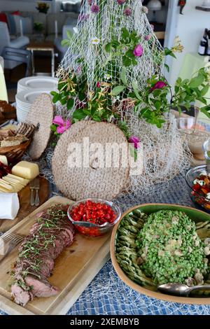 Buffet dinner decorated with old fishing net, wild roses and wild onion flowers.  Midsummer in Sweden, June 2024 Stock Photo