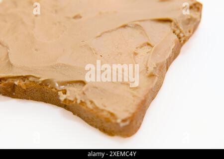 A detailed photo of a single slice of bread generously coated with peanut butter. Perfect for food blogs Stock Photo