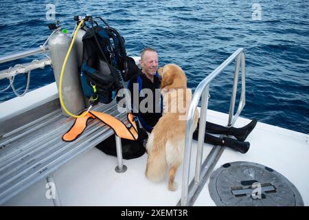 Paraplegic man and his service dog riding in the back of a dive boat; Boynton Beach, Florida, United States of America Stock Photo