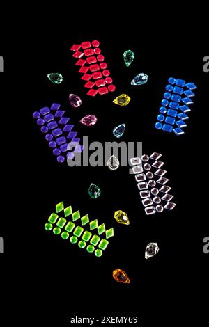 Colorful rows of rhinestones & teardrop jewels are placed at random on a black background. Sparkling designs have rectangle shapes. Colors are bright. Stock Photo
