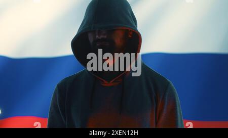 A maniacal russian hacker creating cyber threat alert by holding a skull as concept of cyber espionage and malicious code. Illustration warning of cyber security risks, evil harmful scam. Camera A. Stock Photo