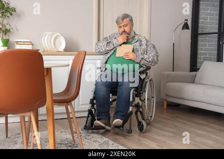 Portrait of sad senior veteran in wheelchair with letters at home Stock Photo