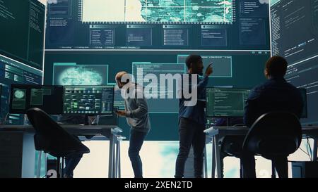 Governmental hackers analyzing cyber threats on big screens, managing important database hacking activity in high tech agency office. Work on cyber defense to protect national security. Camera B. Stock Photo