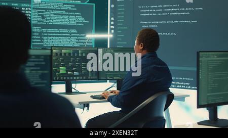 Governmental hackers using advanced software to protect against cyber threats, working in team. Specialists on cyber security, data and network protection unite forces in high tech office. Camera A. Stock Photo