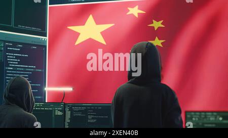 Governmental hacker in high tech office with Chinese flag shown on big screen, IT expert engaged in cyber espionage and criminal activity. Spreading fake news and brainwashing the nation. Camera A. Stock Photo