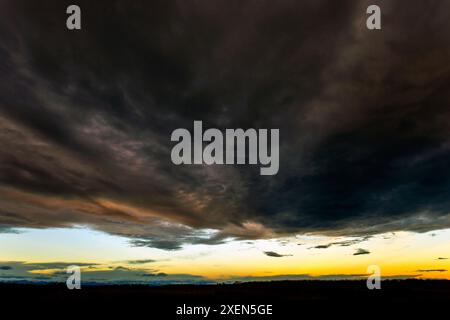 Dramatic storm clouds with a break in the cloud cover and the warm glow of sunset; Calgary, Alberta, Canada Stock Photo