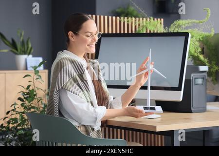 Female engineer with wind turbine model sitting at table in office Stock Photo