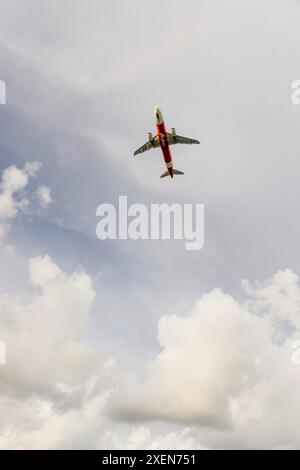 View from directly below of the underside of an airplane flying in a cloudy sky over Mai Khao beach (Airplane beach) in North Phuket, Thailand Stock Photo