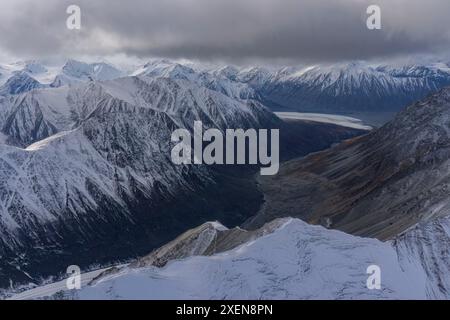 Aerial view of the snow-capped mountains of Kluane National Park under grey clouds, taken during the transition between autumn and winter Stock Photo