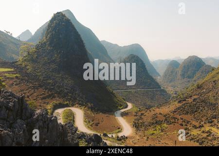 Road with switchback curves winding through a valley with peaked mountains in the countryside of Vietnam Stock Photo