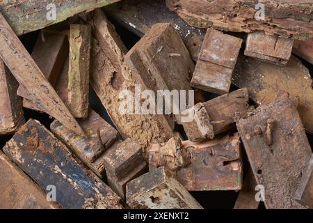 pile of scrape wood pieces with nails in full frame background, left over decayed or rotten weathered wood blocks from construction, unusable Stock Photo