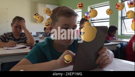 Image of multiple emoticons floating over diverse students studying and using digital tablet Stock Photo