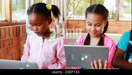 Image of floating dots over diverse girls using digital tablet in classroom at school Stock Photo