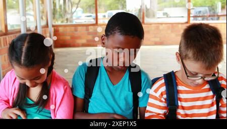 Image of floating dots over diverse girls and boys using digital tablet in classroom at school Stock Photo