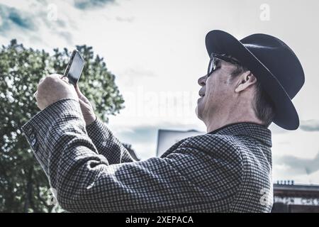An aged man holds his phone in the air trying to get a signal Stock Photo