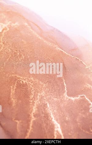 A close-up abstract image of swirling ink in shades of rose gold and grey. The intricate patterns create a unique and mesmerizing visual experience Stock Photo