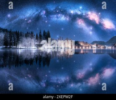 Milky Way arch reflected in water at winter starry night. Landscape with acrhed Milky Way reflected in Bled Lake, Slovenia. Sky with bright stars, sno Stock Photo