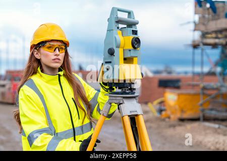 Female site engineer surveyor working with theodolite total station EDM equipment on a building construction site outdoors Stock Photo