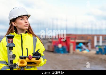 Female site engineer surveyor working with theodolite total station EDM equipment on a building construction site outdoors Stock Photo