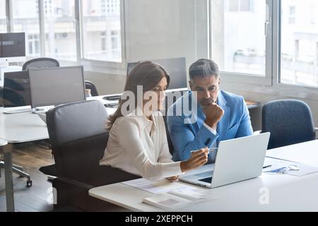 Two busy middle aged business leaders talking working on computer in office. Stock Photo