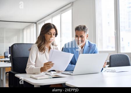 Two executives team working on laptop discussing documents at office meeting. Stock Photo