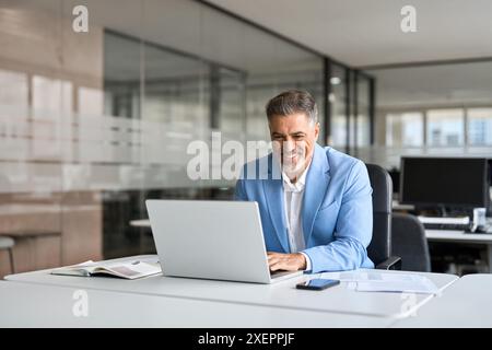Happy senior older professional business man using computer working at desk. Stock Photo