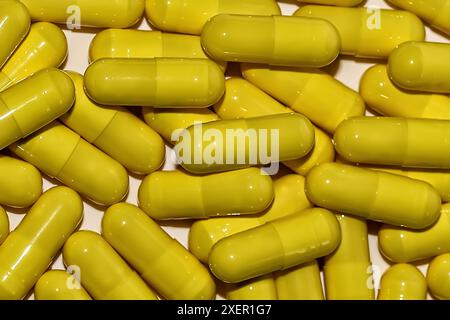 Detail shot of yellow pills piled up on white background. Stock Photo