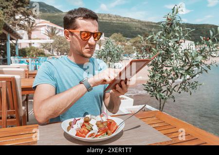 A man looking shocked at an expensive restaurant bill, feeling uneasy about the high cost. Stock Photo