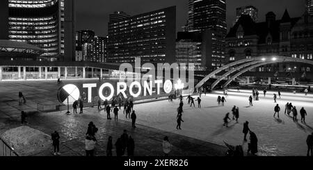 Canadians ice skating on a rink in front of the city hall building at Nathan Philips Square. This large Toronto Sign is a city icon for tourists. Stock Photo