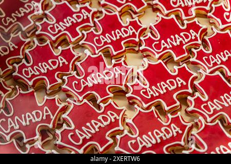 Retail display of bright red  cookies shaped like a maple leaf with the word Canada in a bakery display case. Stock Photo