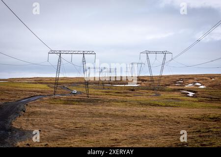High voltage transmission towers and lines in the grasslands of southern Iceland, with dirt winding road below. Stock Photo