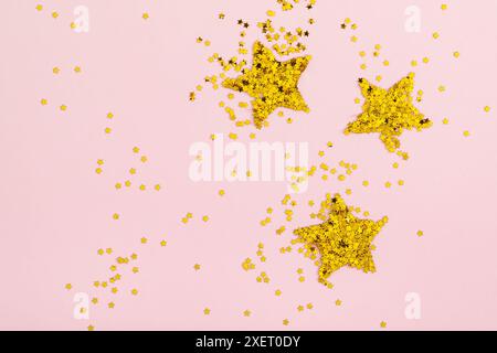 Golden stars glitter confetti on light pink background. Festive holiday pastel backdrop. Minimal concept. Flat lay. Stock Photo