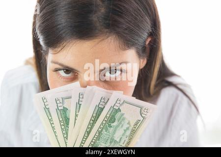 Excited pretty young woman holding money over face, Stock Photo