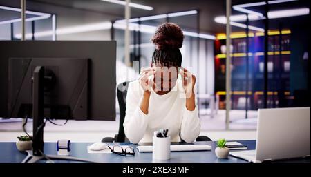 Exhausted Businesswoman Working on Computer in Office, Fighting Stress and Headache Amidst Daily Responsibilities and Pressure. Stock Photo