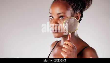Dermatologist using magnifying glass to investigate rosacea skin problem on African American woman for laser treatment at clinic. Stock Photo