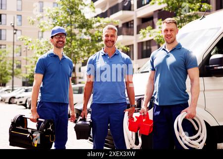Experienced Mechanic in Blue Overalls Posing Proudly Next to Repair Van, Offering Skilled Automotive Services with Care and Precision. Stock Photo