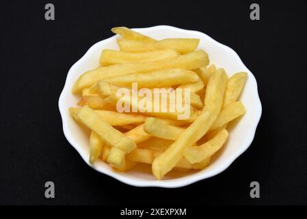 French fries in a white plate on a black background. Delicious fried potatoes. Stock Photo