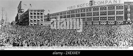 Ford history. It's factory in Highland park Michigan USA was a production facility for the Model T car and has become known for being the first factory in history to assemble cars on a moving assembly line. Picture shows the factory building and chassis in mass outside it.  1916 Stock Photo