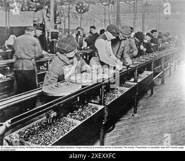 Ford history. It's factory in Highland park Michigan USA was a production facility for the Model T car and has become known for being the first factory in history to assemble cars on a moving assembly line. The workers are seen working at an assembly line. 1914 Stock Photo