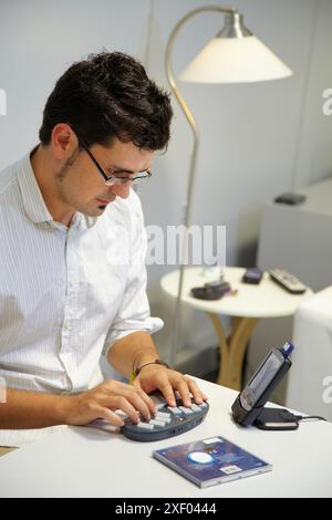 Person labeling a music CD using the braille BlueType keyboard  The person writes the information using the braille bluetooth BlueType keyboard  Later Stock Photo