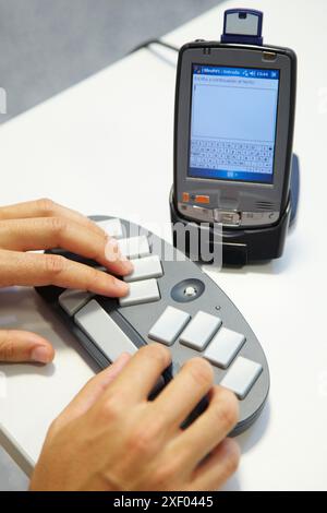 Person labeling a music CD using the braille BlueType keyboard  The person writes the information using the braille bluetooth BlueType keyboard  Later Stock Photo
