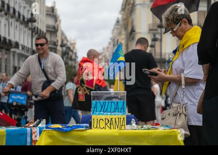 Madrid, Spain. 30th June, 2024. A woman sells souvenirs during a pro-Ukrainian rally. Ukrainian residents in Madrid meet every week in the center of the Spanish capital to support their compatriots at war and raise financial funds to send to their relatives punished by the war. Credit: SOPA Images Limited/Alamy Live News Stock Photo