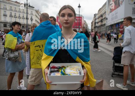 Madrid, Spain. 30th June, 2024. A woman sells souvenirs during a pro-Ukrainian rally. Ukrainian residents in Madrid meet every week in the center of the Spanish capital to support their compatriots at war and raise financial funds to send to their relatives punished by the war. Credit: SOPA Images Limited/Alamy Live News Stock Photo