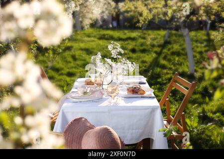 Beautiful table setting with spring flowers in garden on sunny day Stock Photo