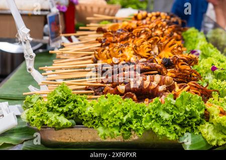 Grilled octopuses and squids on skewers. Thai strret food on night market. Asian food in Bangkok, Thailand Stock Photo