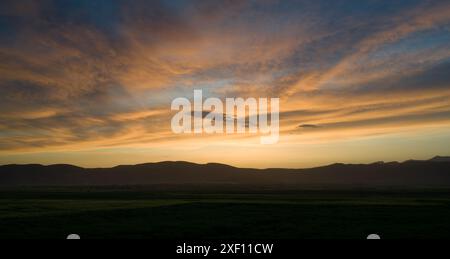 Silhouette of sunset over fields and mountains Stock Photo