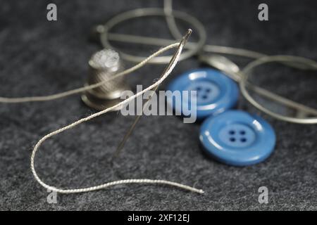 Close-up of gray fabric ready for tailoring with scissors, thread, needle foxglove and buttons Stock Photo