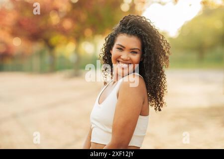 Young Woman With Curly Hair Smiling in a Park Stock Photo