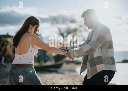 Joyful couple dancing on a beach during their vacation, sunlit natural setting Stock Photo
